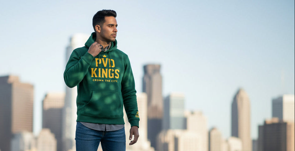 Person wearing a green PVD hoodie with text, standing against an urban skyline.